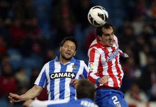 Atletico Madrid's Godin and Real Sociedad's de la Bella challenge for a high ball during their Spanish first division soccer match in Madrid