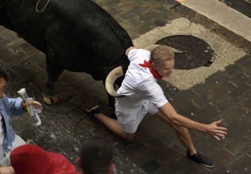 A runner is caught between the horns of a Fuente Ymbro fighting bull on Santo Domingo street during the sixth running of the bulls of the San Fermin festival in Pamplona