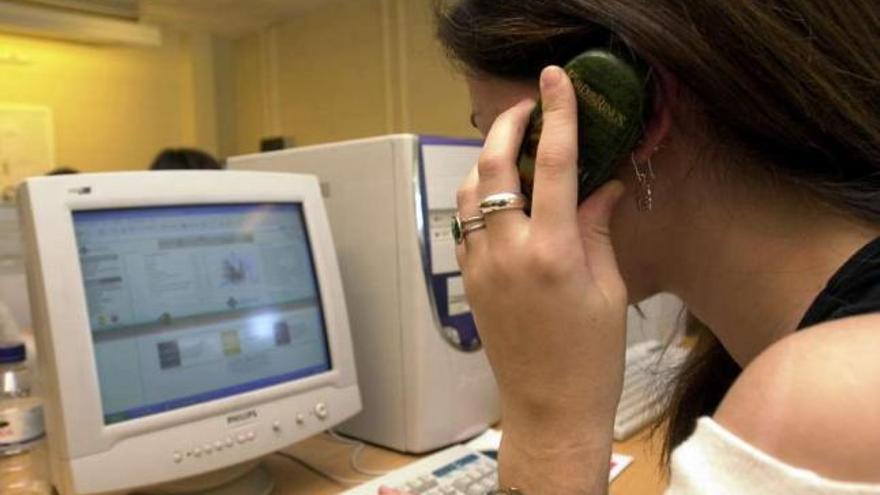 Una mujer atiende una llamada delante de un ordenador. / la opinión