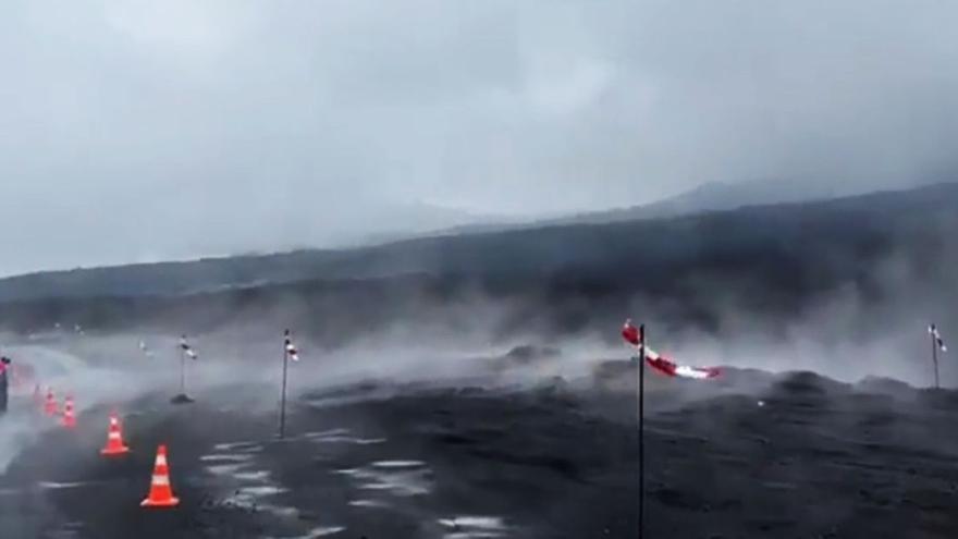 Varios vehículos transitan, entre nubes de vapor, por una carretera afectada por la erupción del volcán de Tajogaite.