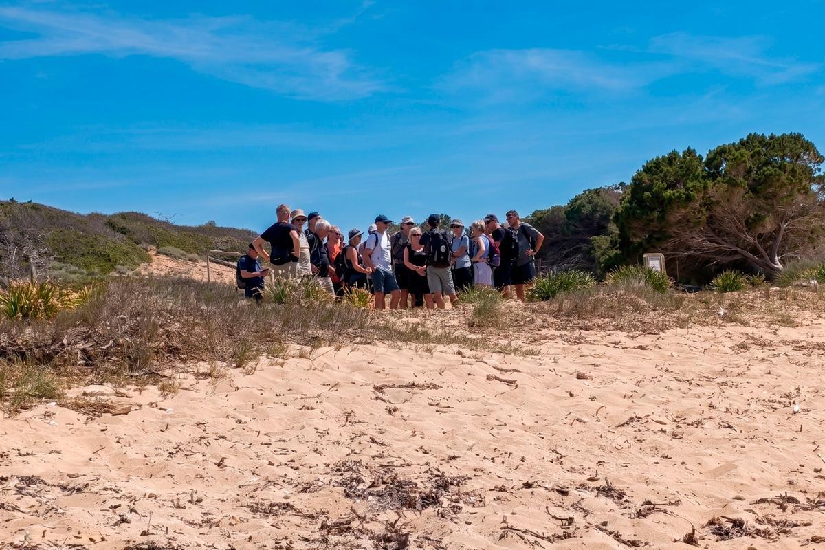Grupo de turistas escuchando las explicaciones del guía, entre la playa de es Dolç y la playa de es Carbó