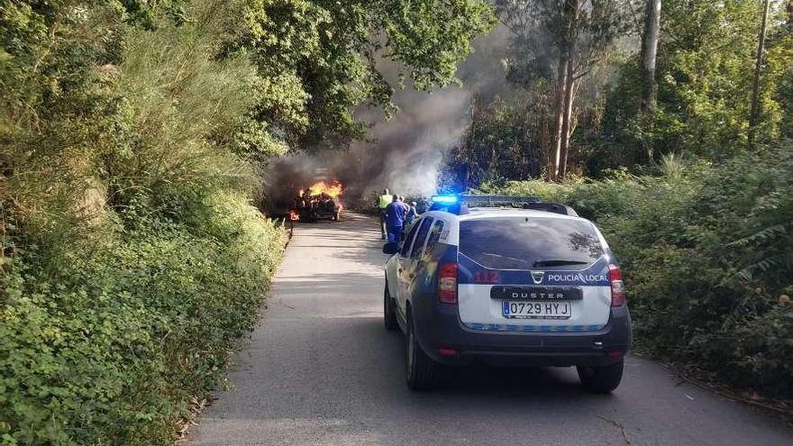 El remolque en llamas en el vial de Chans a Hermelo con el vehículo de la Policía cortando el paso. // FdV