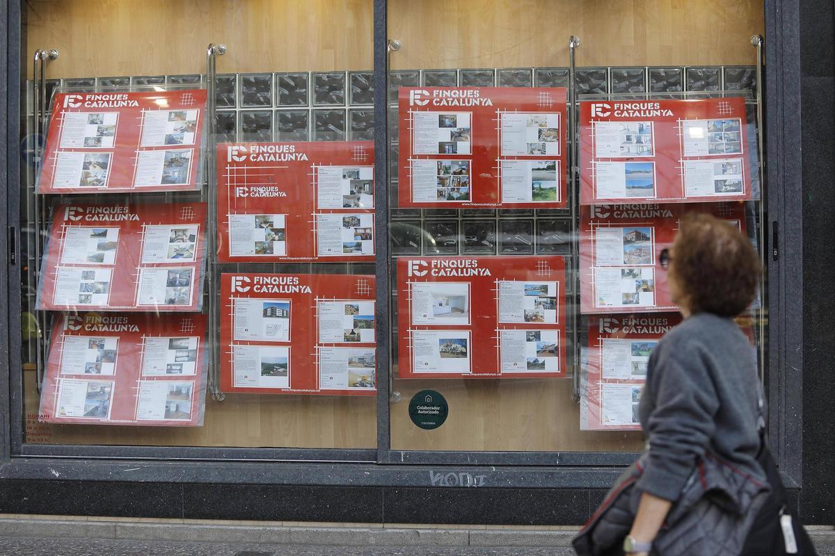 Una persona davant l'aparador d'un immobiliària a Girona.