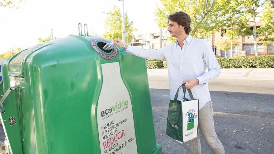 Un ciudadano deposita los envases de vidrio en el contenedor.