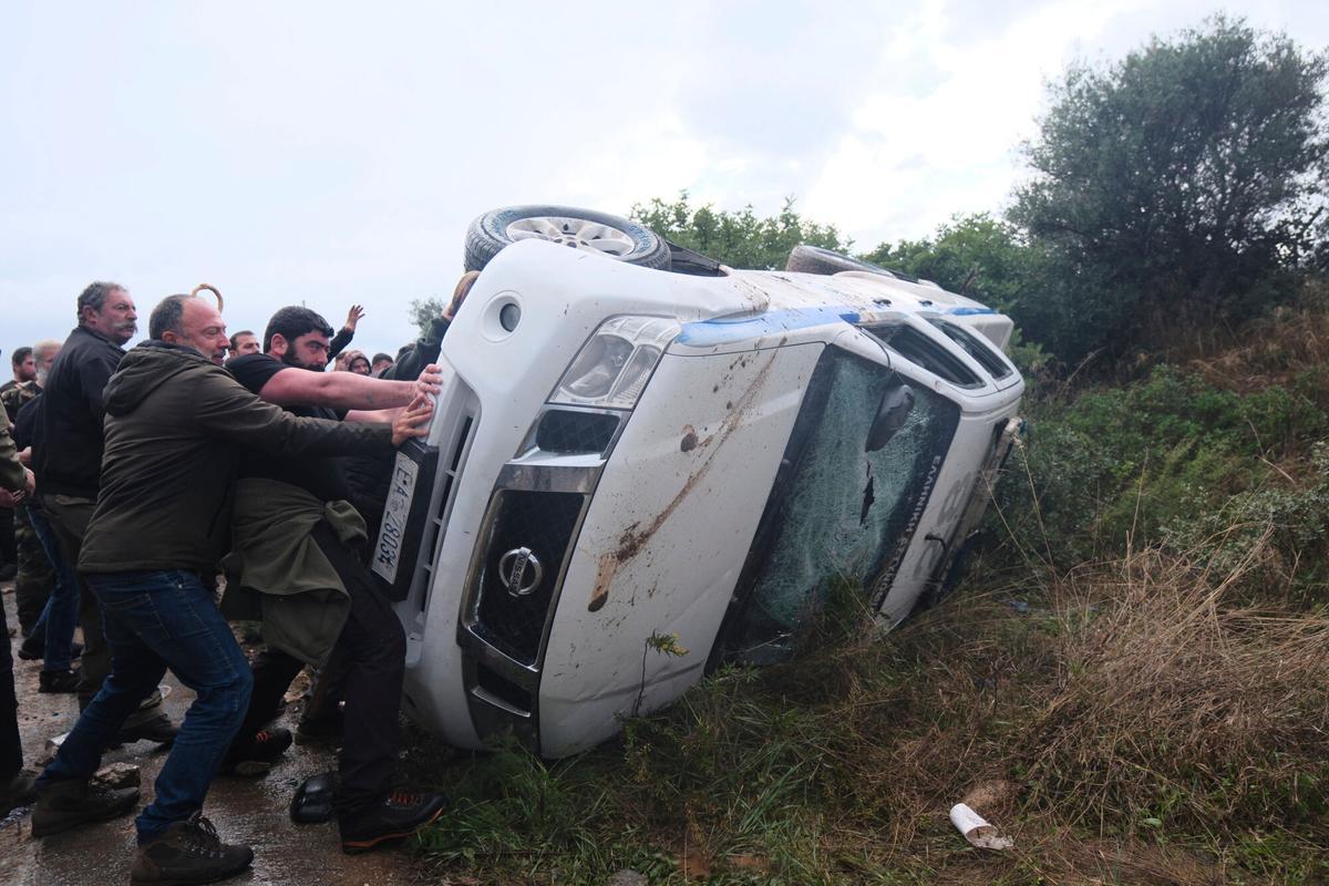 Farmers overturn a police vehicle during clashes with officers blocking their march to Chanias airport on Crete, Greece, Monday, Dec. 8, 2025, amid protests over delayed EU farm subsidies. (AP Photo/Giannis Angelakis)