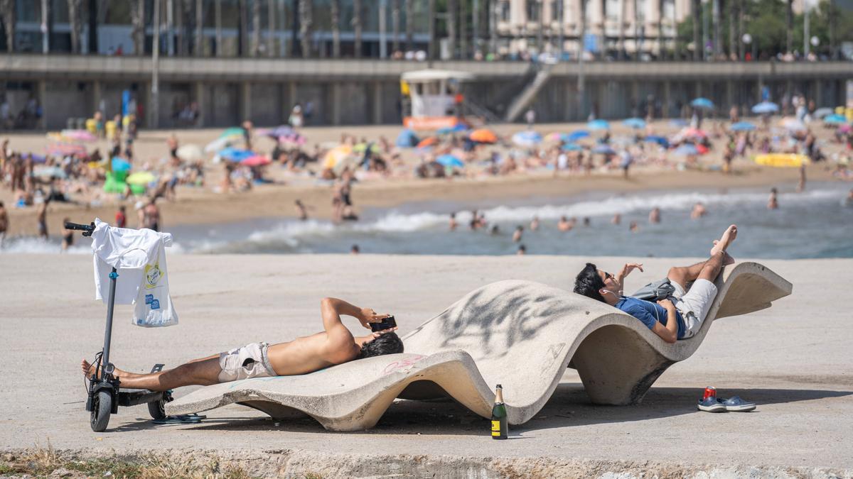 Varias personas descansan en la playa de Barcelona durante un episodio de ola de calor.