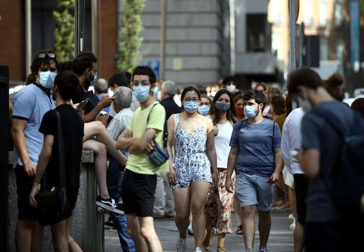 Varias personas caminan con mascarilla por una calle del centro de Madrid.