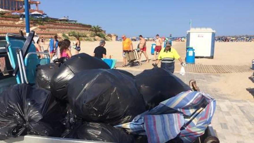 Un operario retira basura y enseres en la playa de La Zenia.