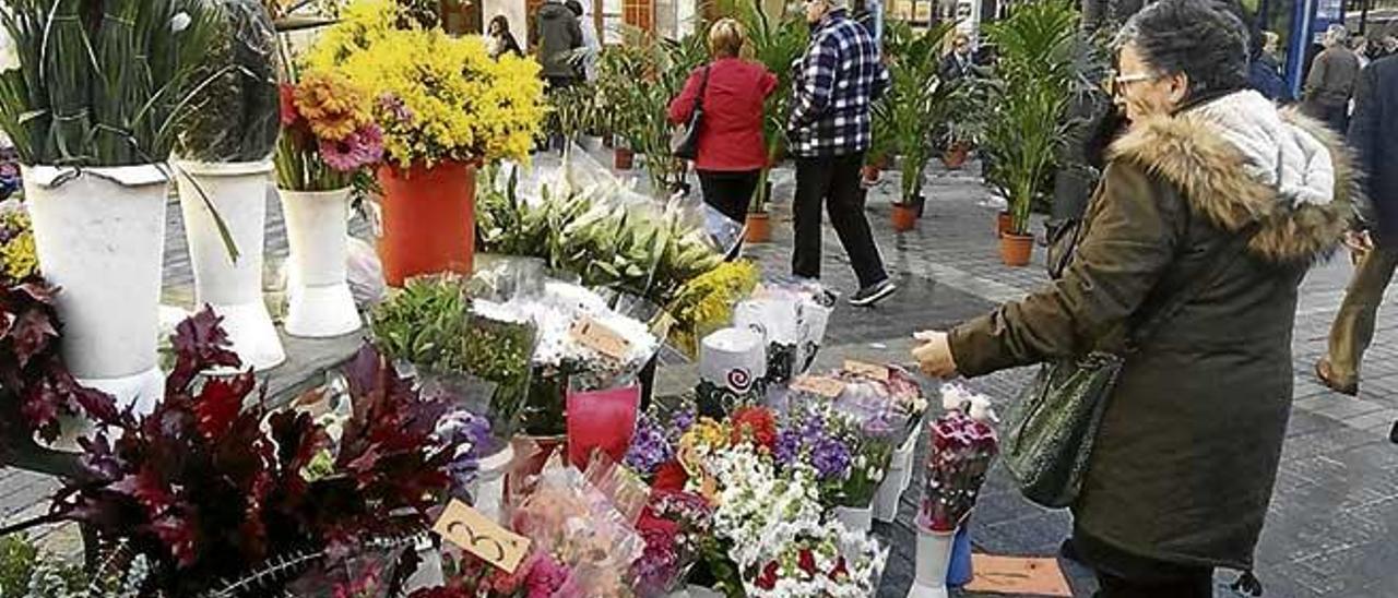 Varias clientas observan uno de los puestos de flores.