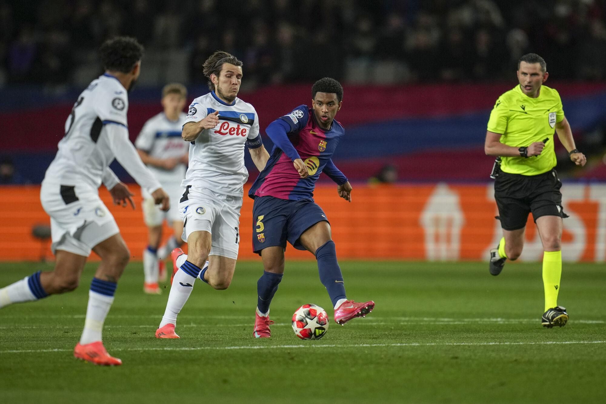 English referee Michael Oliver, right, follows the action as Atalanta's Marten de Roon, left, vies for the ball with Barcelona's Alejandro Balde during a Champions League opening phase soccer between Barcelona and Atalanta match at the Lluis Companys Olympic stadium in Barcelona, Spain, Wednesday, Jan. 29, 2025. (AP Photo/Emilio Morenatti)