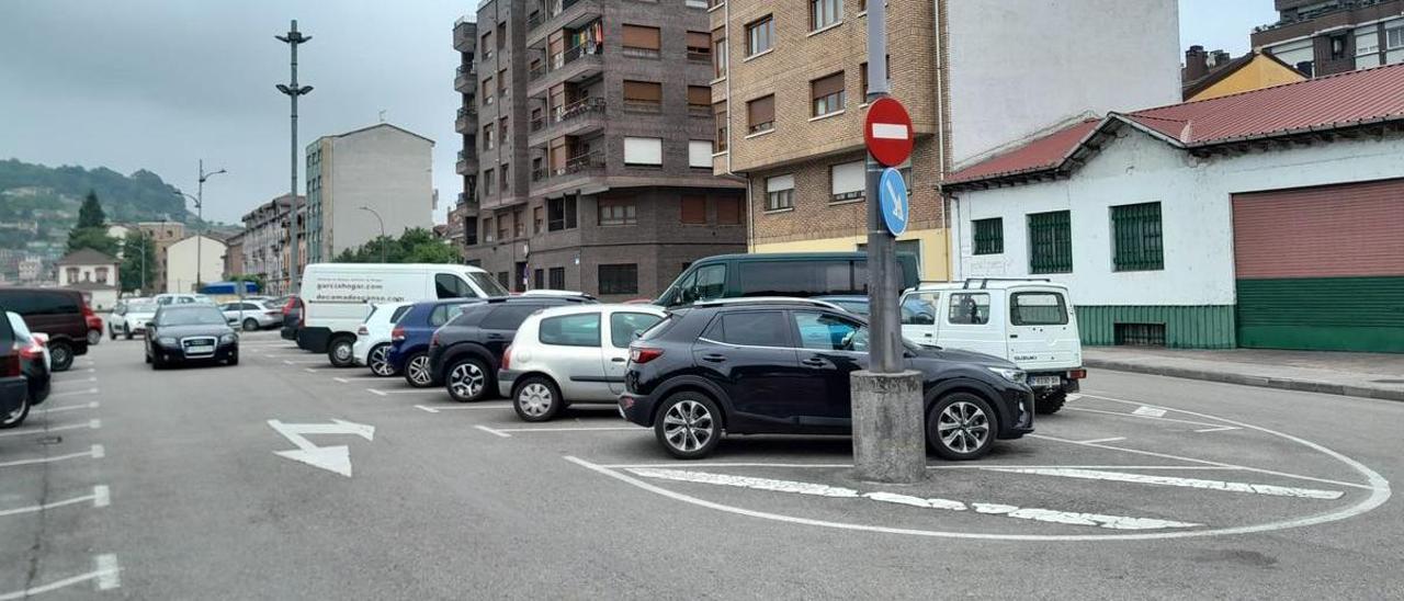 Dos vehículos buscan dónde estacionar en el parking de la Renfe en Sama, lleno de coches. | L. M. D.