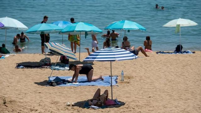 Gent refrescant-se a la platja de la Barceloneta durant una altra jornada de calor intensa.