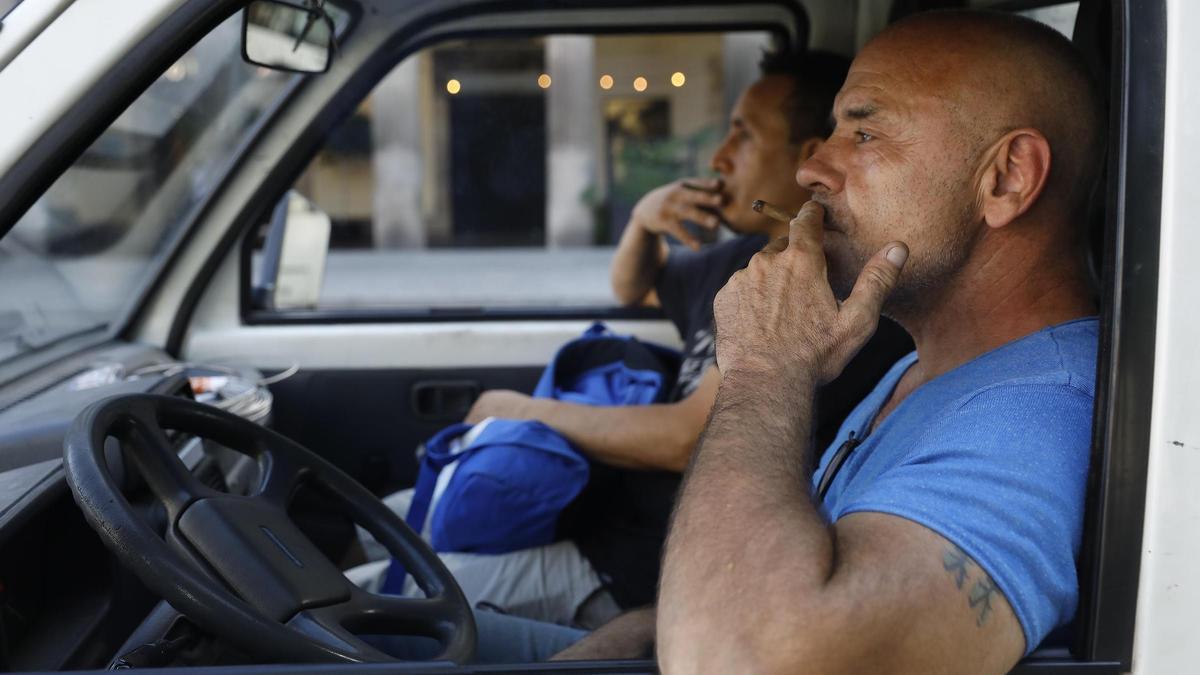 Dos hombres fumando en el interior de un coche.