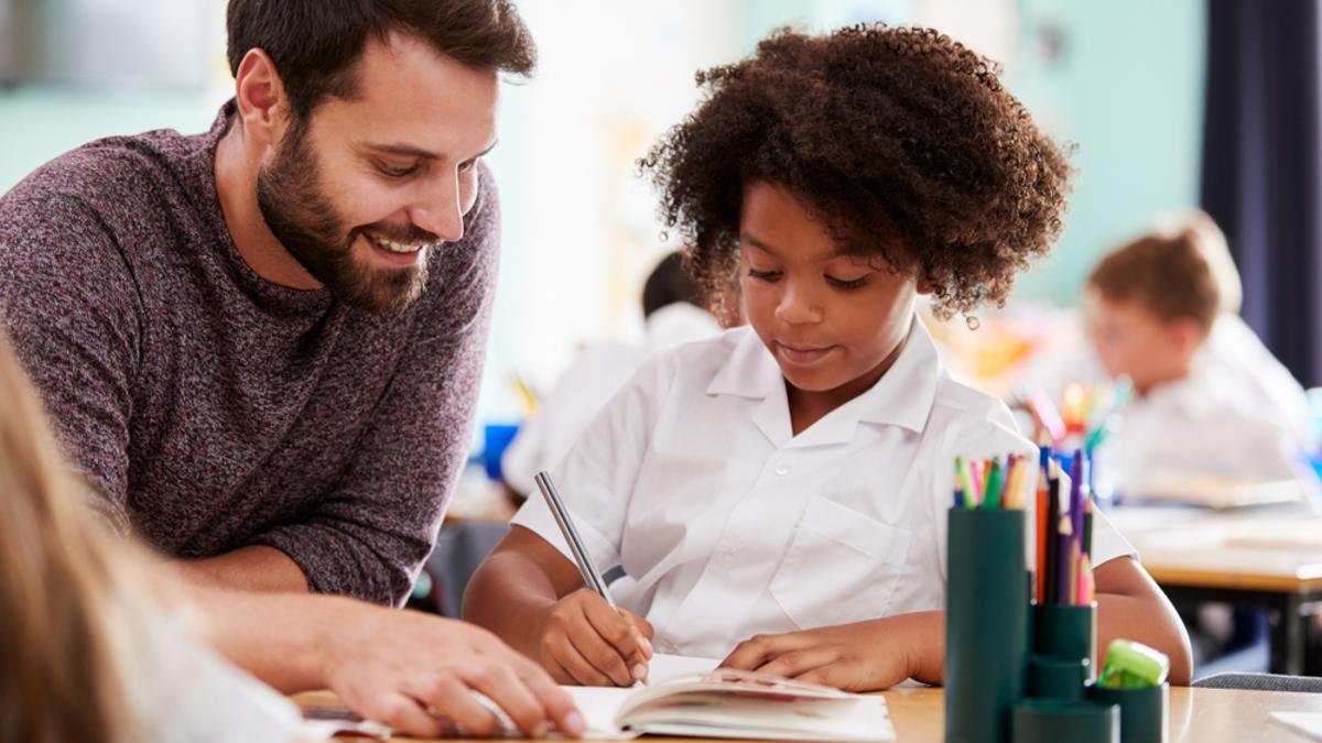 Un profesor ayuda a una alumna con sus tareas.