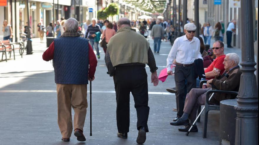 Dos personas mayores pasean por la calle Triana.