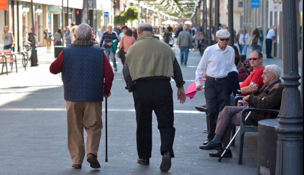 Dos personas mayores pasean por la calle Triana.