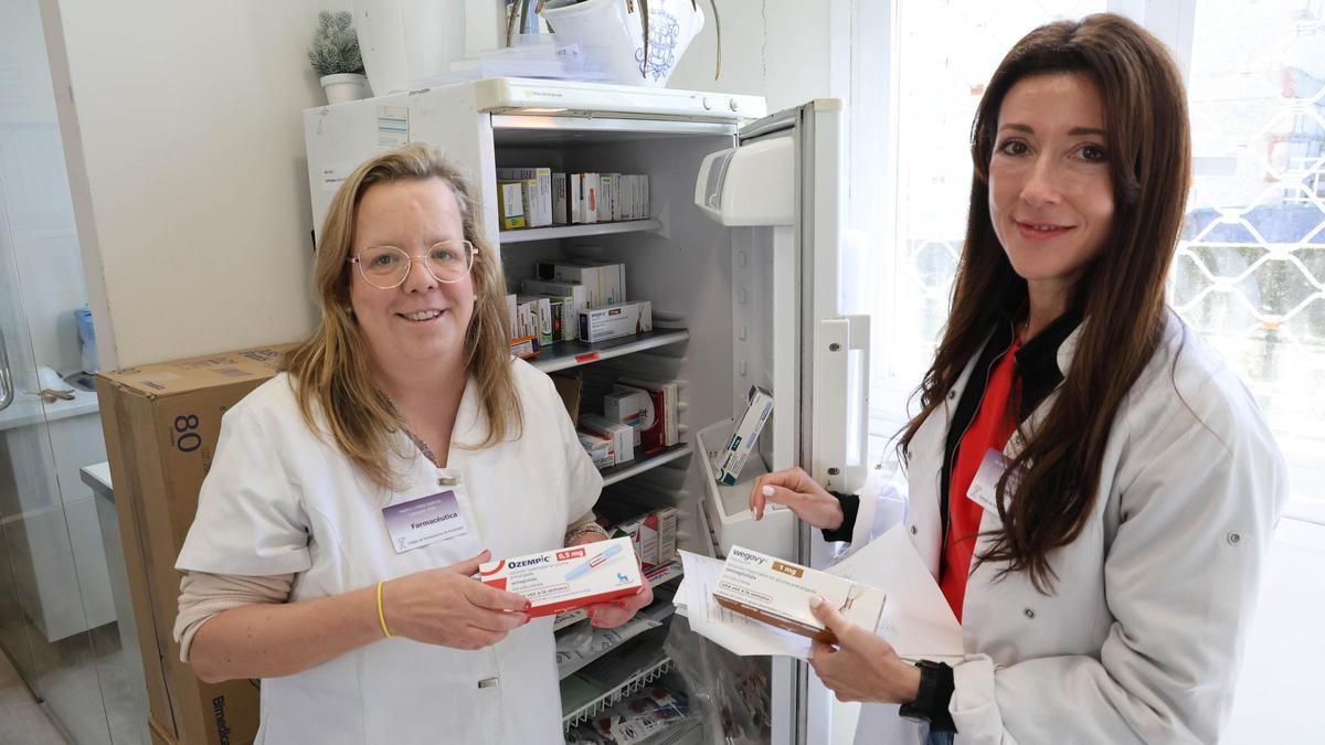 Marta Otero y Alba Rodríguez, de la farmacia Priegue Rodríguez, en la nevera con medicamentos.