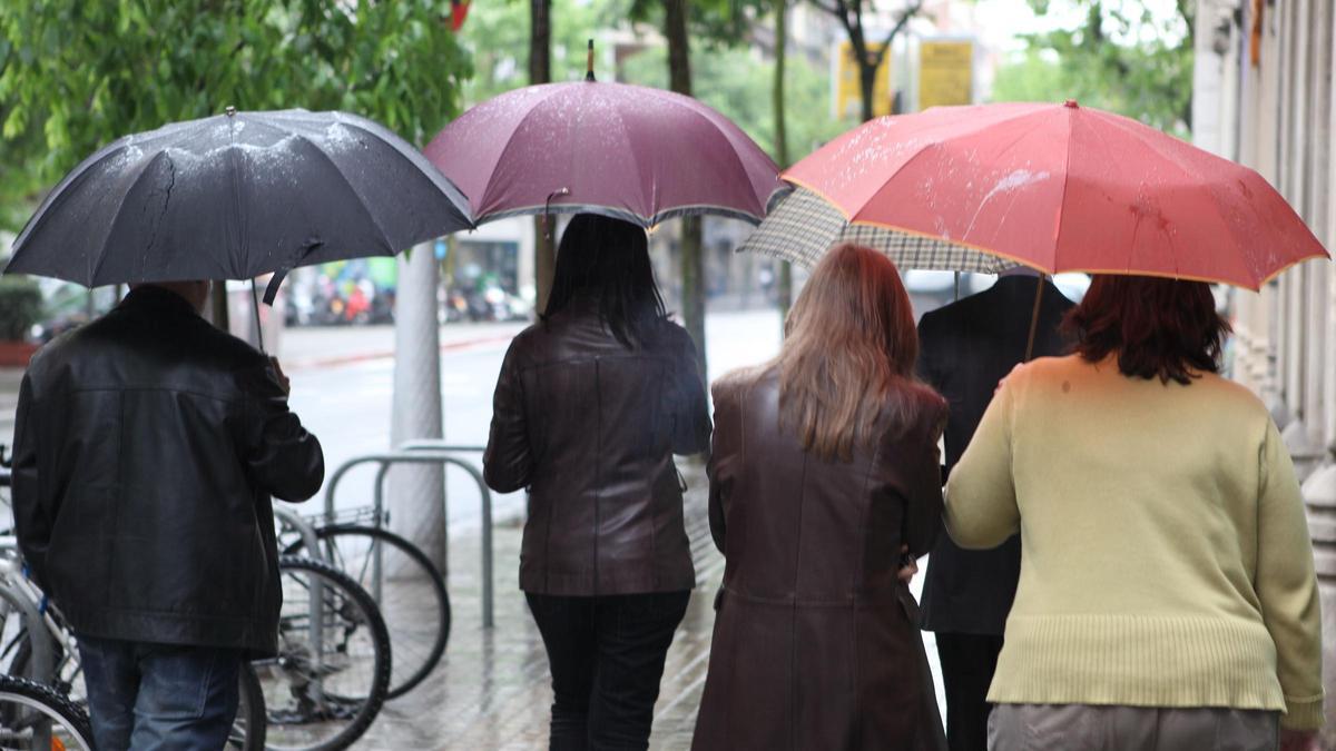 Un grupo de personas camina bajo la lluvia con sus paraguas