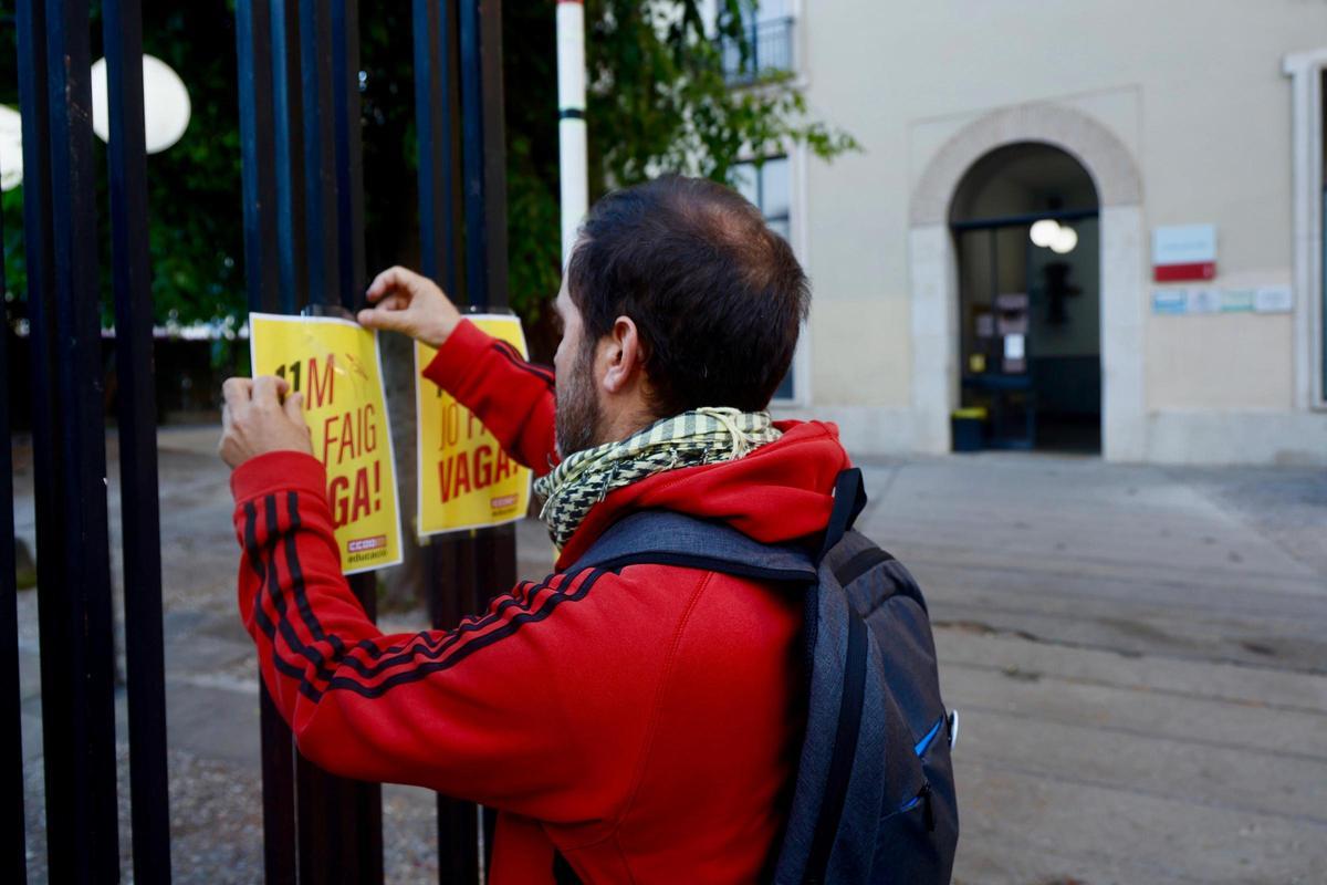 Un representante sindical pega un cartel reivindicativo sobre la huelga en las puertas del IES Lluís Vives de València