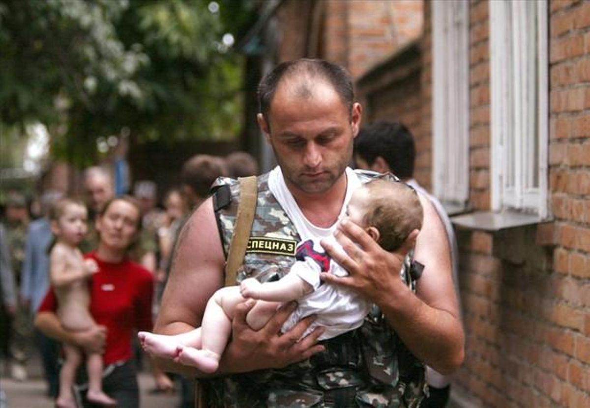 A Russian police officer carries a released baby from a school seized by heavily armed masked men and women in the town of Beslan in the province of North Ossetia near Chechnya, in this September 2, 2004 file photo.