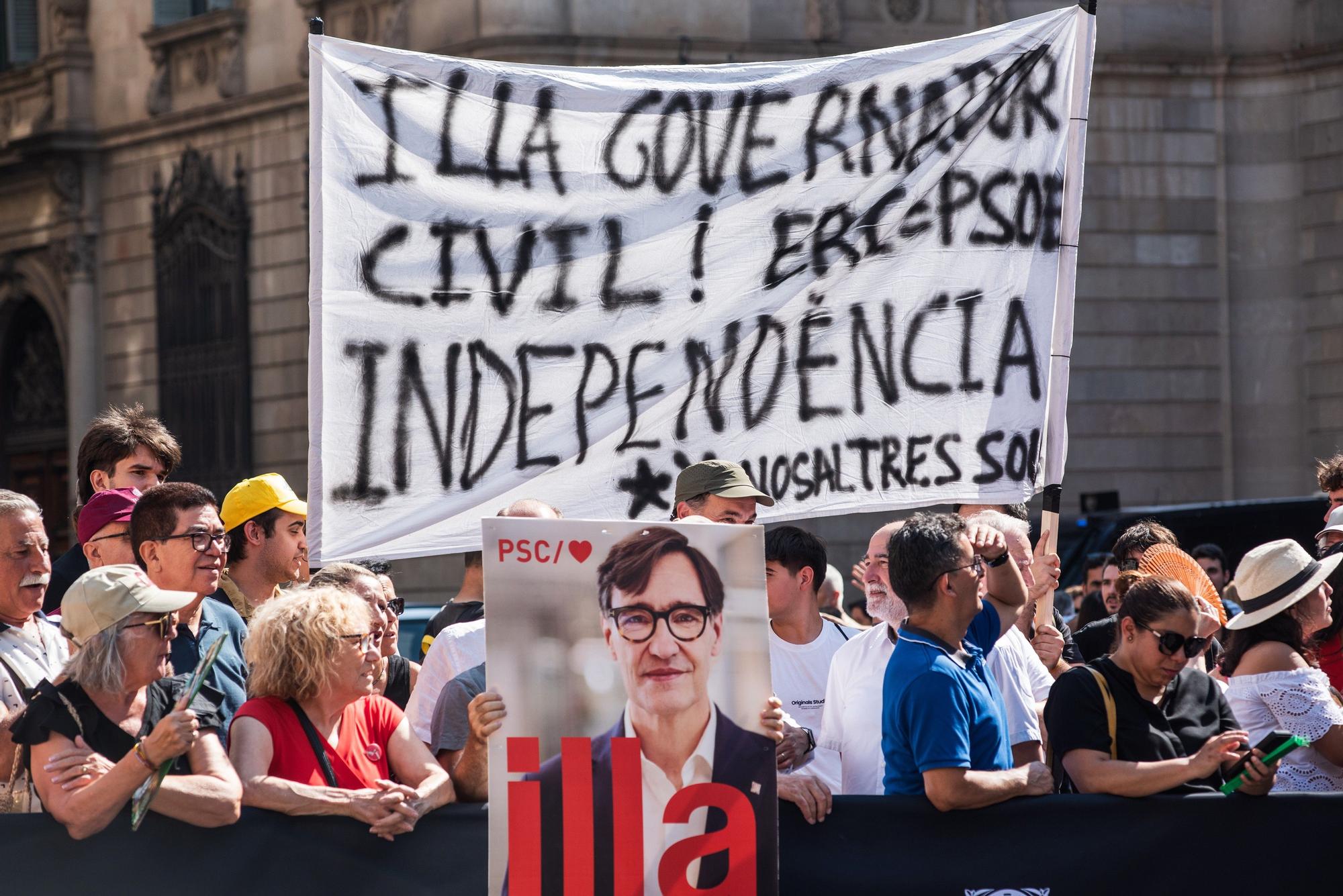 Varias personas con carteles antes de la toma de posesión de Salvador Illa como president de la Generalitat, en la plaza de Sant Jaume.