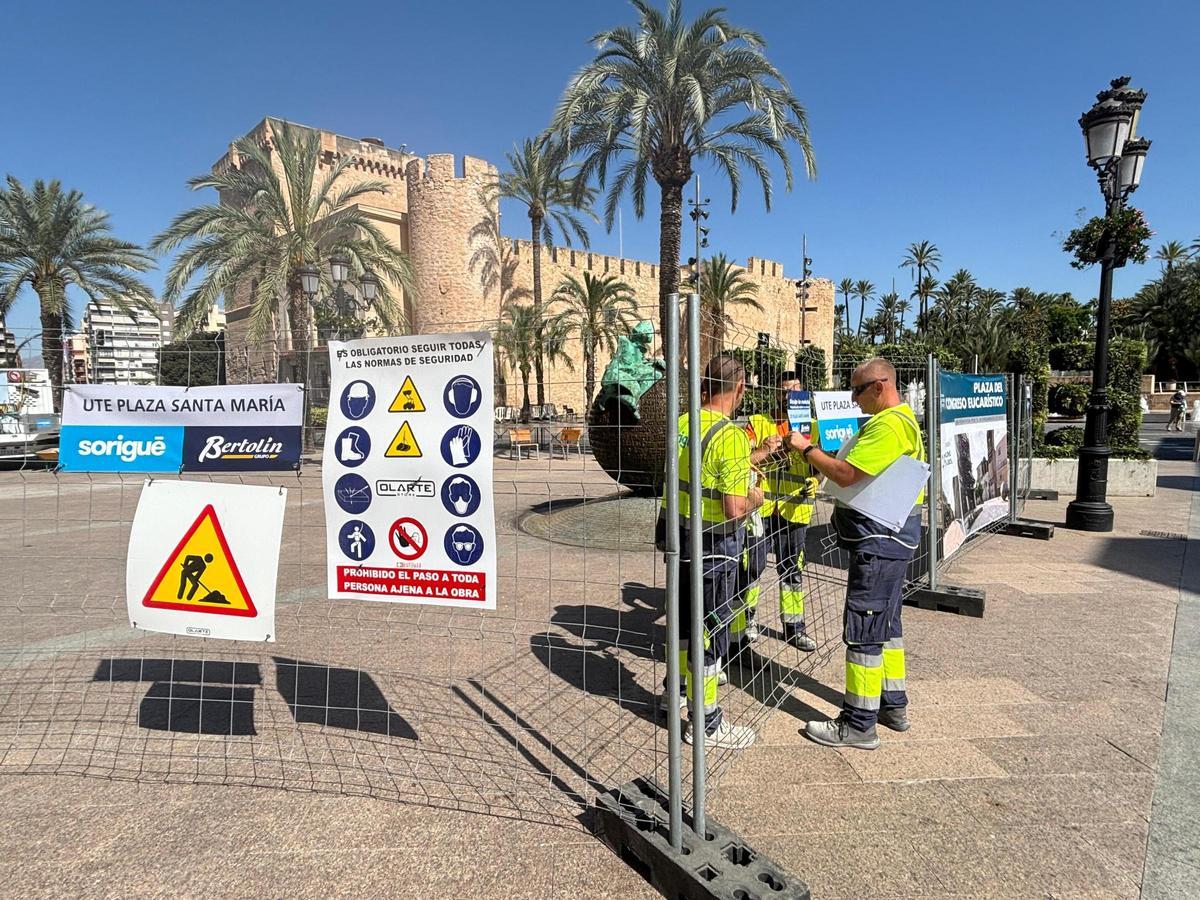 Operarios de la unión de empresas adjudicataria colocando las vallas de obra en la plaza del Palau, con la escultura «Geografía de la memoria» de Eutiquio Estirado