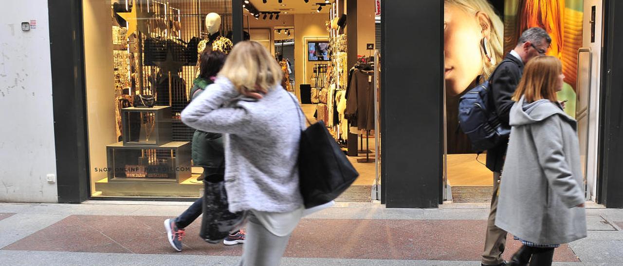 Mujeres pasando delante de una tienda que acaba de abrir en la calle Hospital.