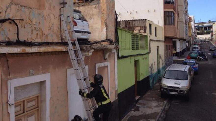 Un bombero sube con una escalera hasta la azotea, donde se encuentra el coche aparcado.