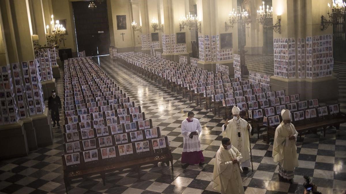 El arzobispo de Lima bendice a víctimas del covid-19, representados con fotografías en la catedral.