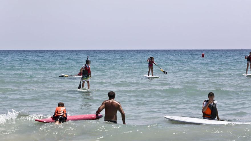 Jovenes practicando paddle surf en la playa de San Juan en Alicante.