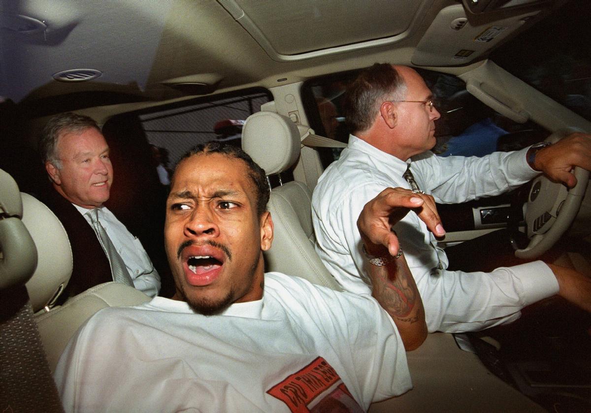 Philadelphia 76ers Allen Iverson, front, reacts to reporters and photographers swarming around his car as he leaves the Criminal Justice Center in Philadelphia on Monday, July 29, 2002. At rear are his attorneys Tom Shuttleworth, left, and Larry Woodward. A judge tossed out all but one charge against the NBA All-Star, who was accused of storming into his cousin's apartment with a gun and threatening two men while looking for his wife. Municipal Court Judge James DeLeon said that Iverson would stand trial on two misdemeanor counts of making terroristic threats against the men. (AP Photo/Philadelphia Daily News, Jennifer Midberry). paisano 2002 dentro del coche serio _ horizontal