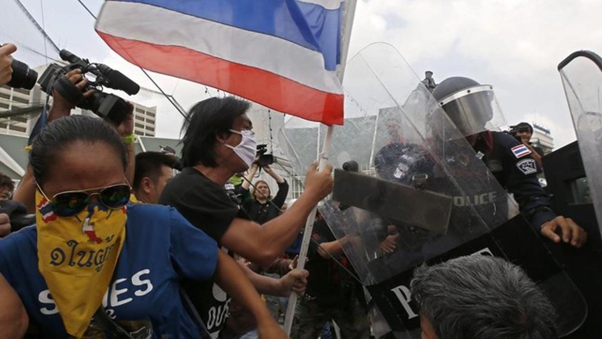 Manifestantes antigubernamentales se enfrentan a los agentes antidisturbios cerca de la sede del Gobierno en Bangkok, este viernes.