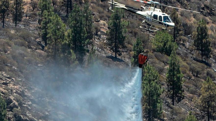 Un helicóptero arroja agua en una zona afectada entre Artenara y Gáldar.