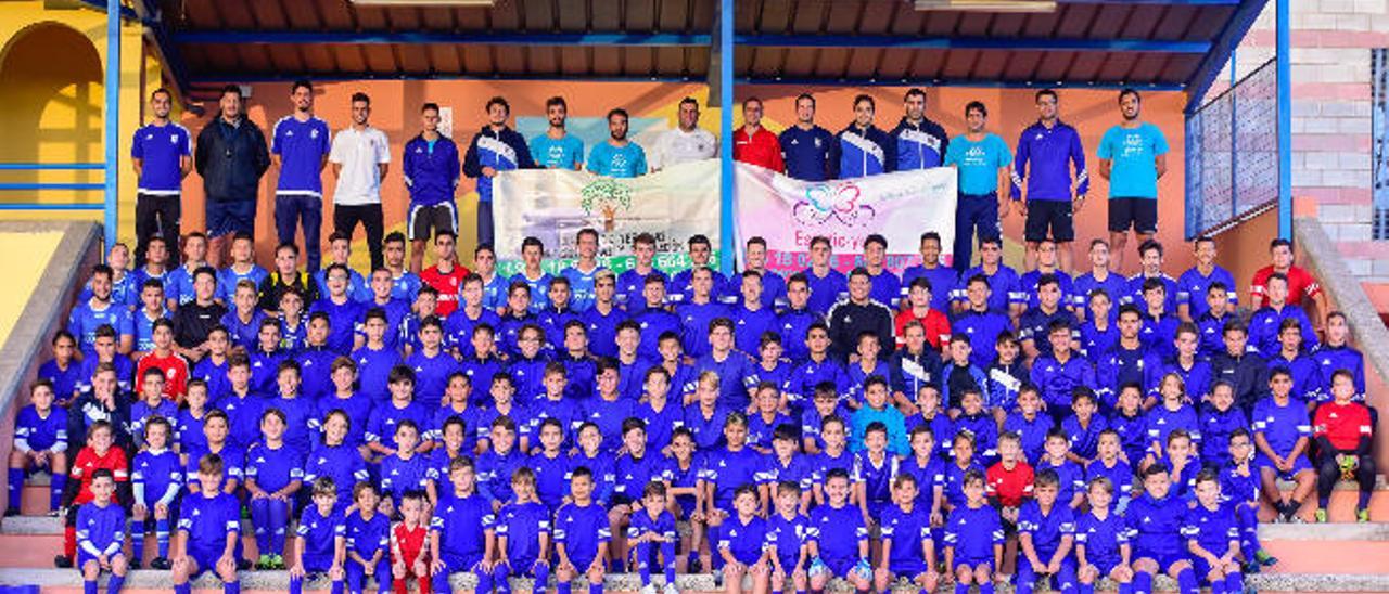 Buena parte de la cadena del CD Doramas, con jugadores y técnicos, en la grada del campo de fútbol de la Ciudad Deportiva de Cruce de Arinaga.