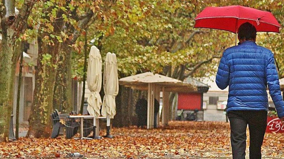 Un home passeja pel Passeig Pere III en un dia de pluja