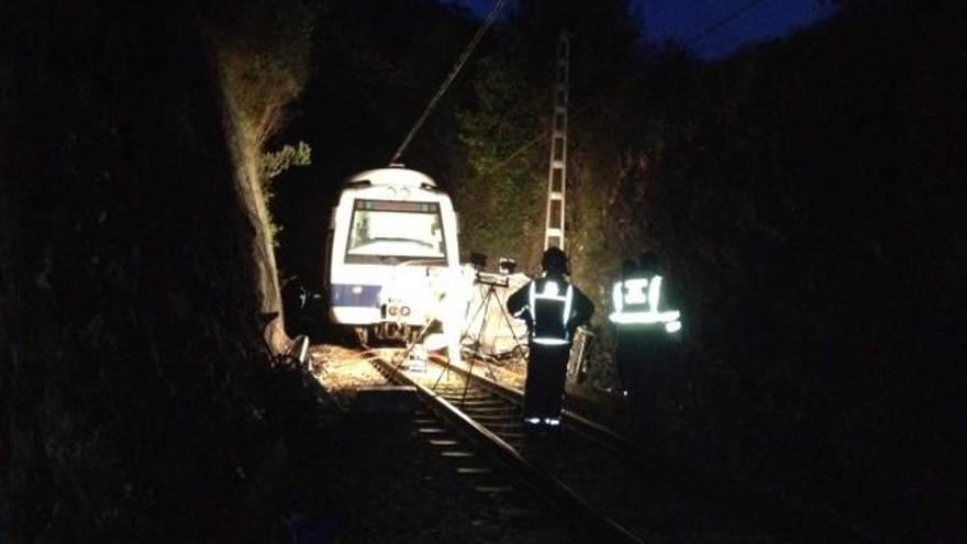 Bomberos y agentes de la Guardia Civil, junto al coche siniestrado y el tren de Feve.