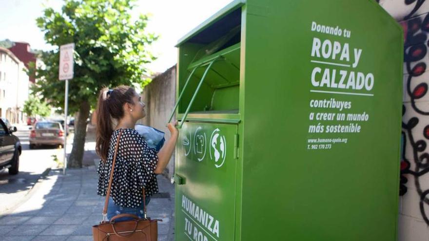 Una joven deposita ropa en uno de los contenedores de reciclaje instalados en Sotrondio.