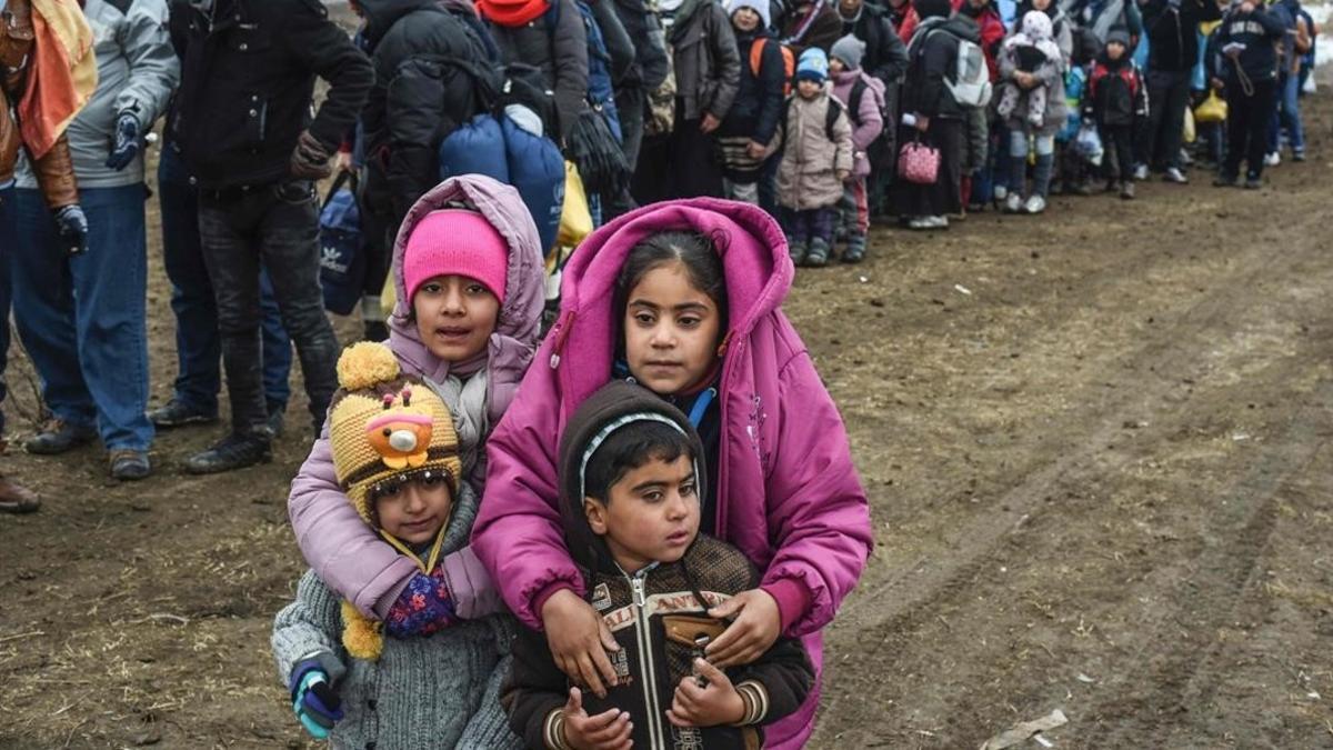 Unos niños sirios esperan junto a otros refugiados para cruzar la frontera entre Macedonia y Serbia, cerca de Miratovac, el 26 de enero del 2016.