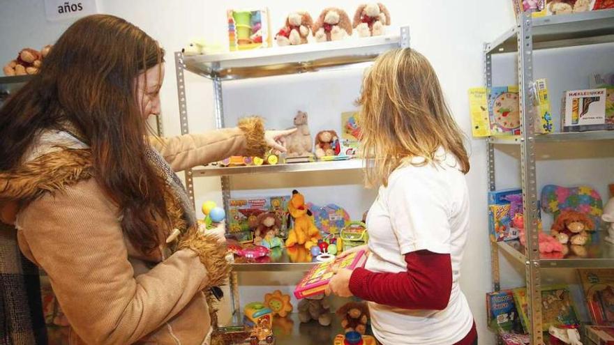 Una mujer selecciona los juguetes para sus hijos con ayuda de una voluntaria, ayer, en A Coruña. 13fotos
