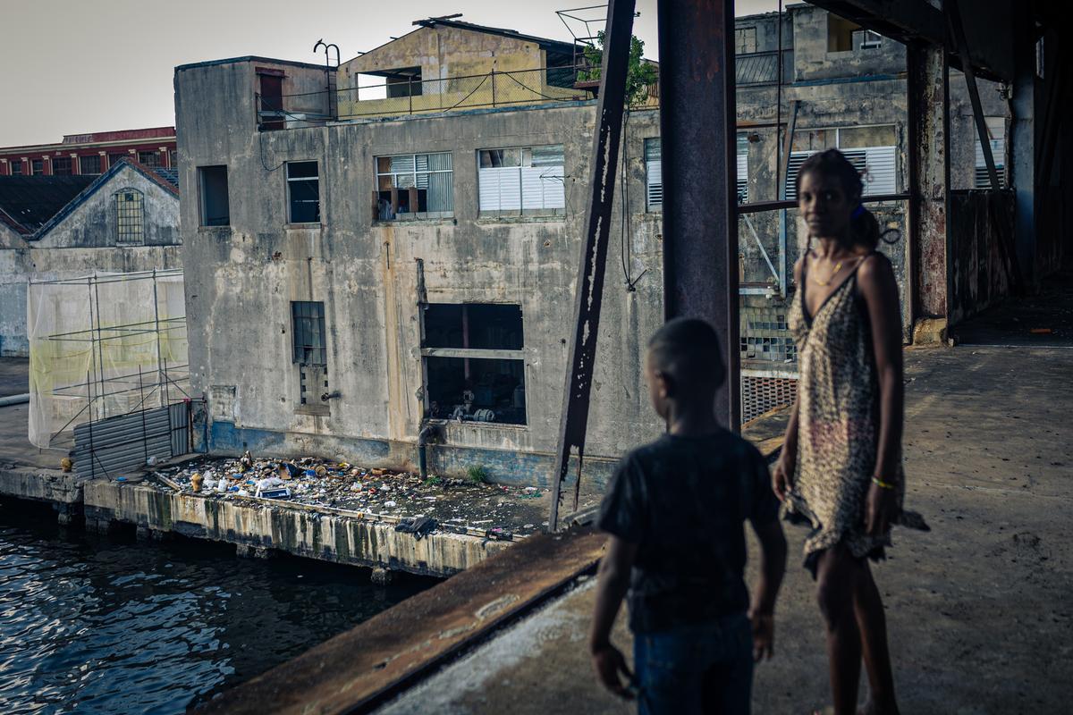 Yurislandi (8) y Sally (32) observan la acumulación de residuos en el refugio situado en Muelles La Coubre, una antigua oficina portuaria que ha estado abandonada durante años hasta que el gobierno la utilizó como alojamiento temporal para las personas que perdieron su hogar.