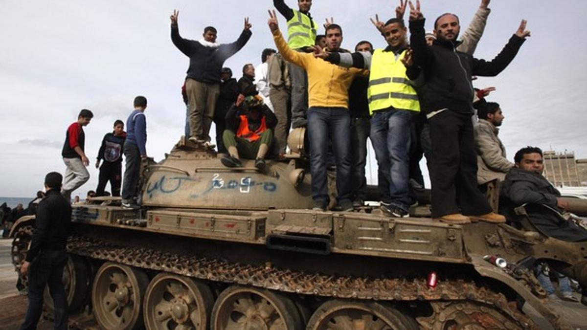 Varios manifestantes hacen el signo de la victoria sobre un tanque del Ejército, el miércoles, en Bengasi.