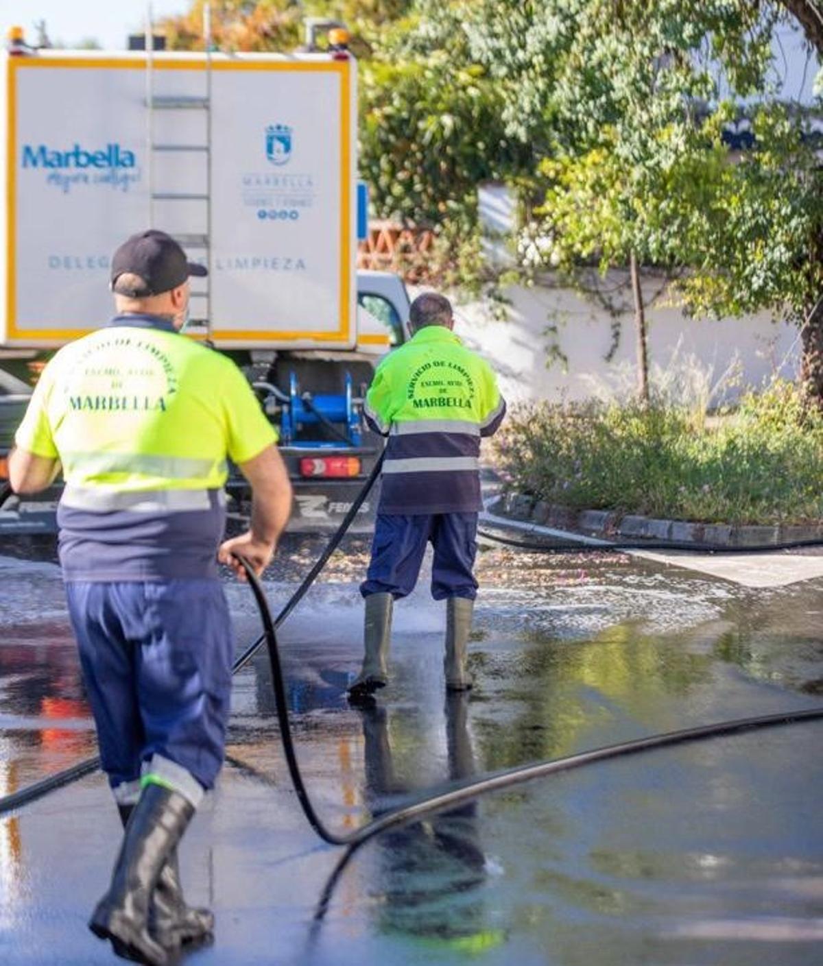 Dos operarios de Limpieza realizan un baldeo en una de las calles de Marbella.
