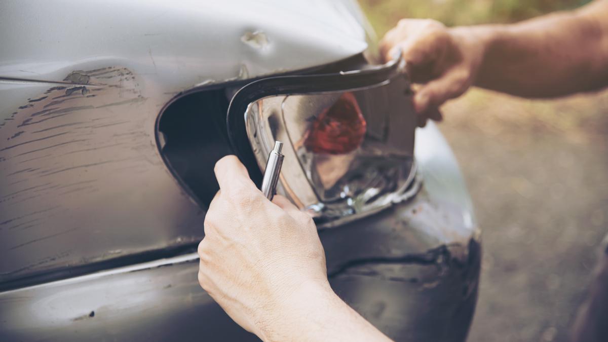 Un agente de seguros trabaja en la reparación de un coche tras haber sufrido un golpe