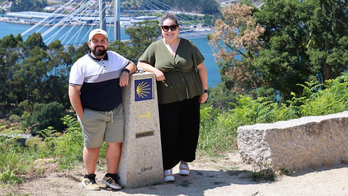 Pablo Santos y Andrea Fernández, con un mojón del Camino y el puente de Rande detrás.