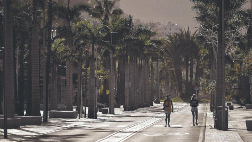 Dos personas caminan por una avenida desierta de Arona.