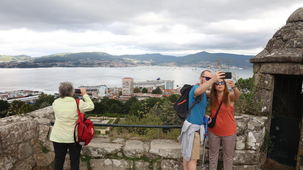Cruceristas en O Castro haciéndose fotos con su buques de fondo atracados en el puerto de Vigo