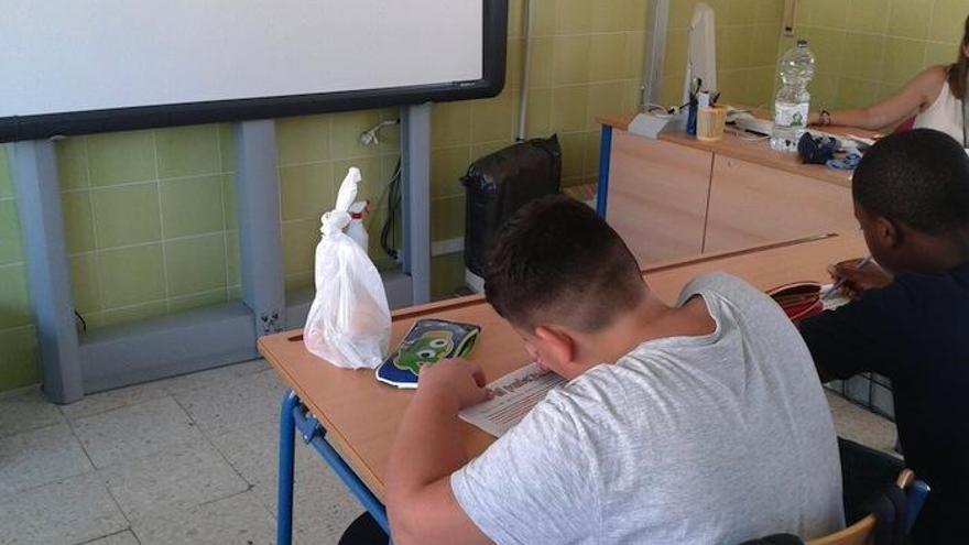 Niños estudian en clase, con su bolsa de la merienda en el pupitre.