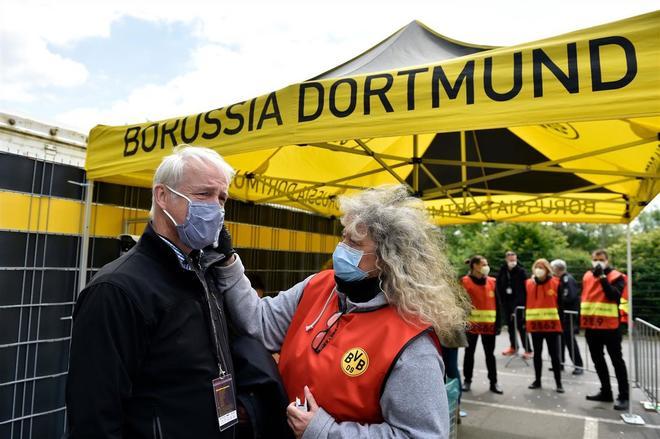 Una empleada del Dortmund le toma la temperatura a un periodista a la entrada del estadio