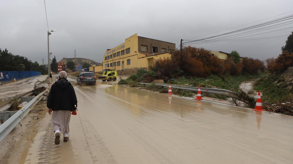 Un peatón cruza un puente sobre uno de los cauces que se desbordó.