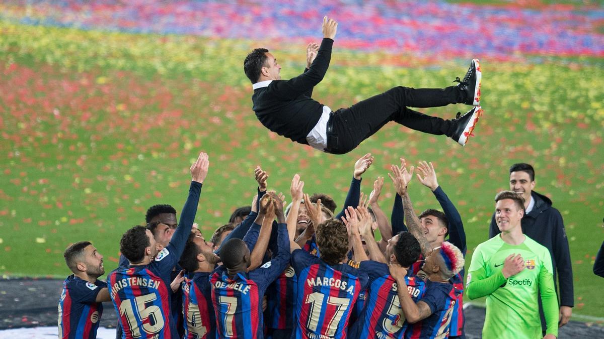 Los jugadores del Barça mantean a Xavi tras recibir el trofeo de la Liga en el Camp Nou.